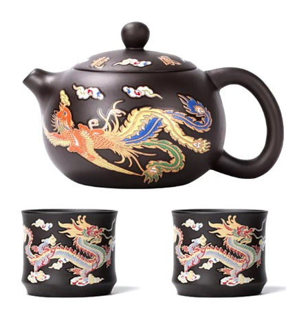 Black teapot and two matching cups with dragon designs on a white background